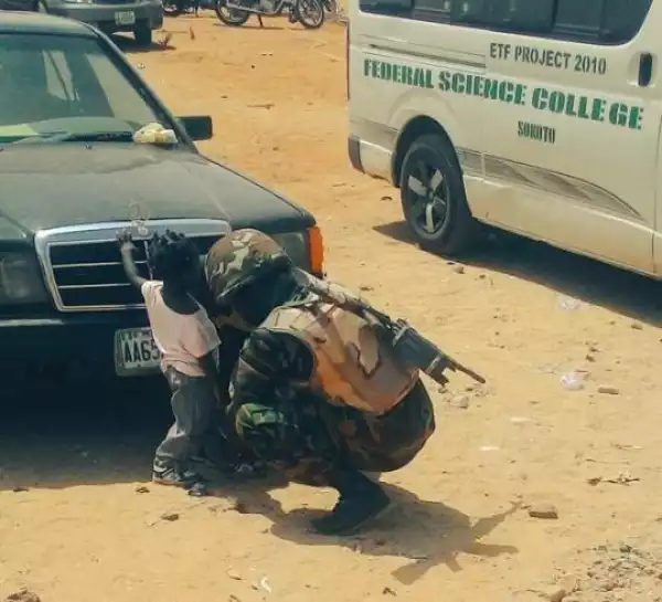 Lovely!! See Photo Of Nigerian Soldier Helping Little Girl To Put Her Shoes On