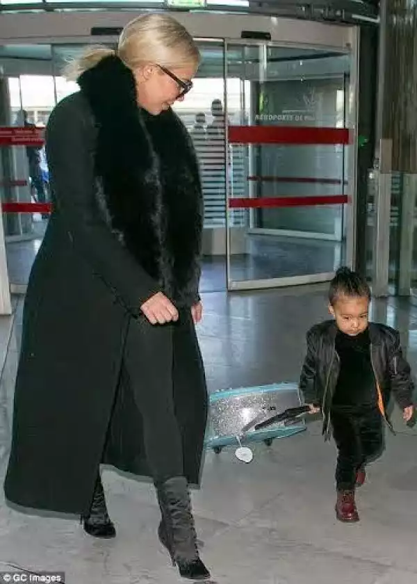 North West handles her own suitcase as she & Kim jet out of Paris