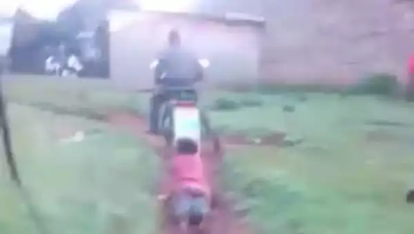 Policeman incites outrage after being filmed dragging a woman tied to his motorcycle on a dirt path (video)